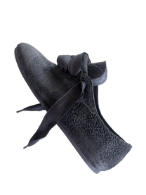 Side view of a black K-Two Studios Sash Flat with pointed sculptural shape and tied sash detail.
